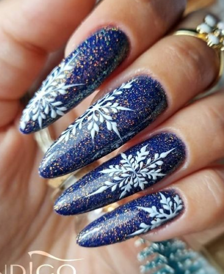 Diseños de uñas de invierno navideños con copos de nieve y brillo azul profundo