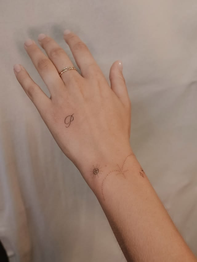 Elegant cursive initial dainty small tattoo idea.