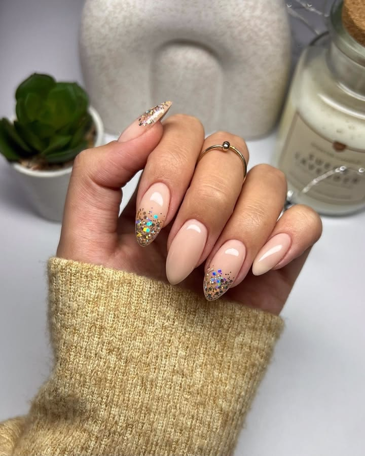 Nude almond nails with multi-color glitter tips.